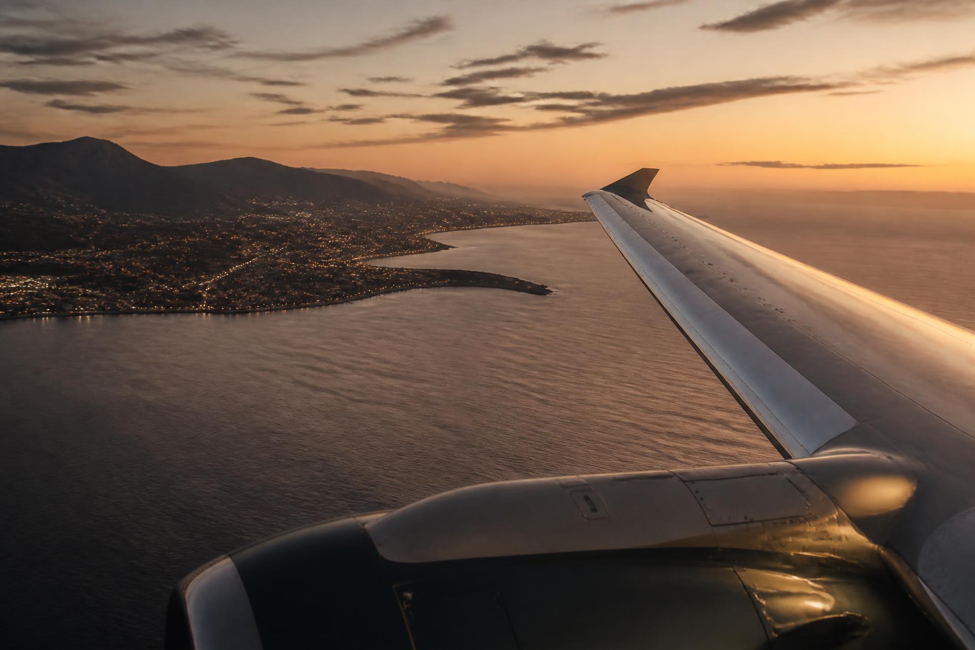 Coastline and distant city lights seen from the air at dusk